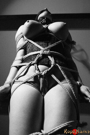 Hooded model Amely is roped and strung up by ropes in an